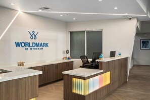 A reception desk with a logo, two computer monitors, a phone, and a small plant.