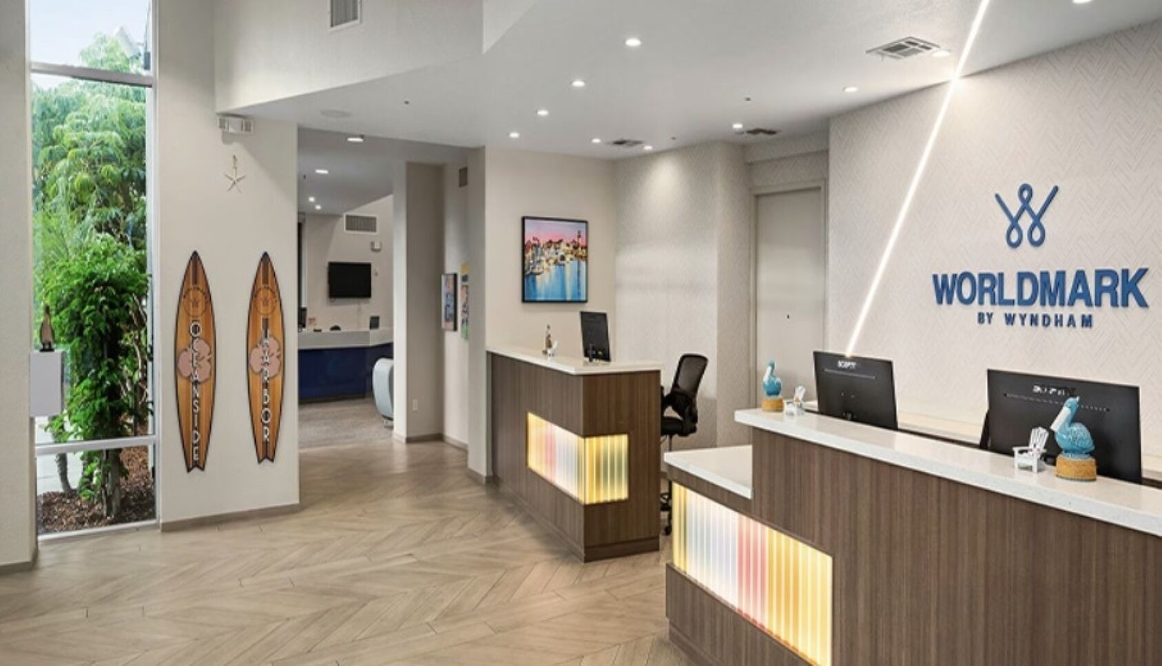 A reception area with a modern design, featuring a reception desk, a wall-mounted sign, and a painting.