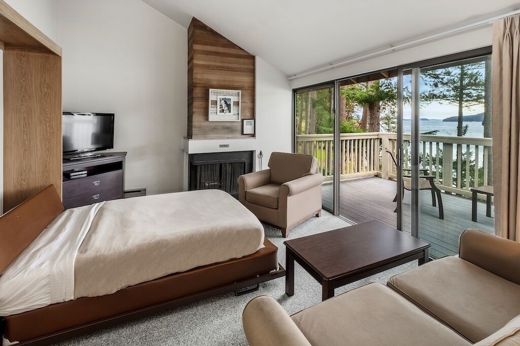 Habitación de hotel con cama, televisión, sofá, mesita de centro y balcón con vistas al mar.