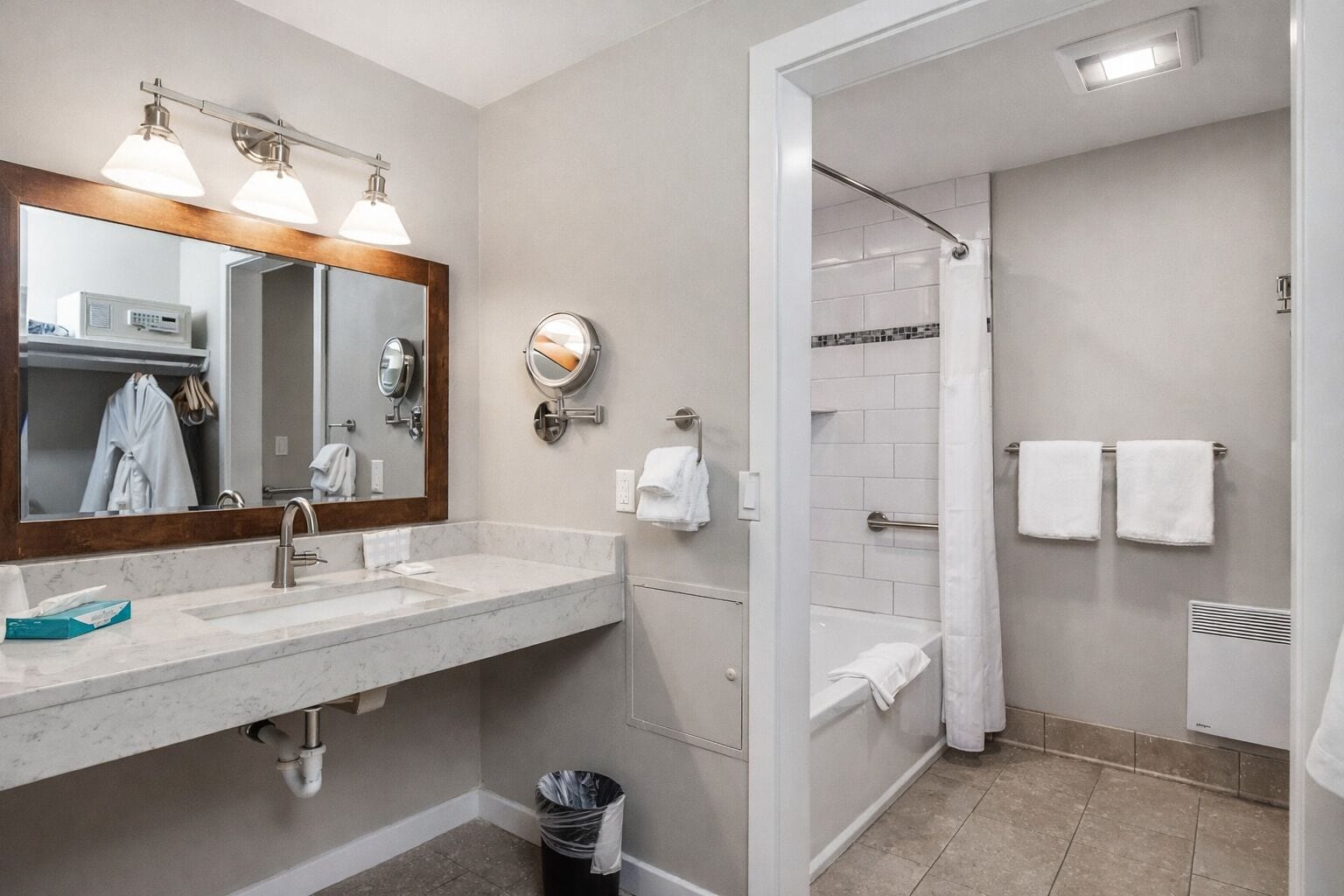 A modern bathroom with a marble sink, a large mirror, a shower with a glass door, and white towels.