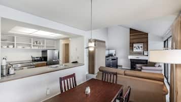 Una cocina moderna con electrodomésticos integrados, un comedor con mesa de madera y una sala de estar con sofá y televisor.