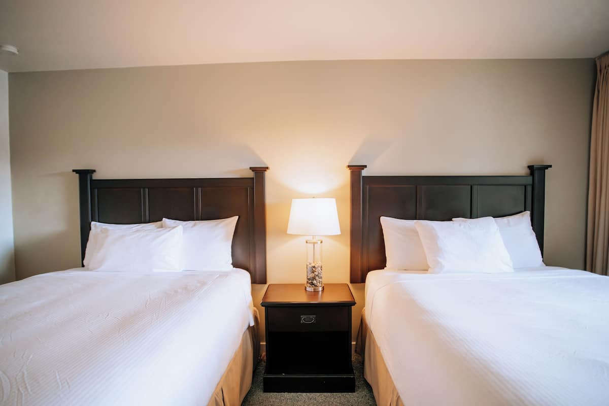 Een hotelkamer met twee bedden, een nachtkastje met een lamp en een klein lade.