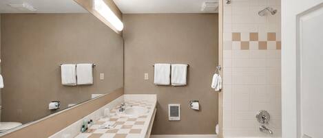 Un baño moderno con un espejo grande, un lavamanos, una bañera y una zona de ducha.