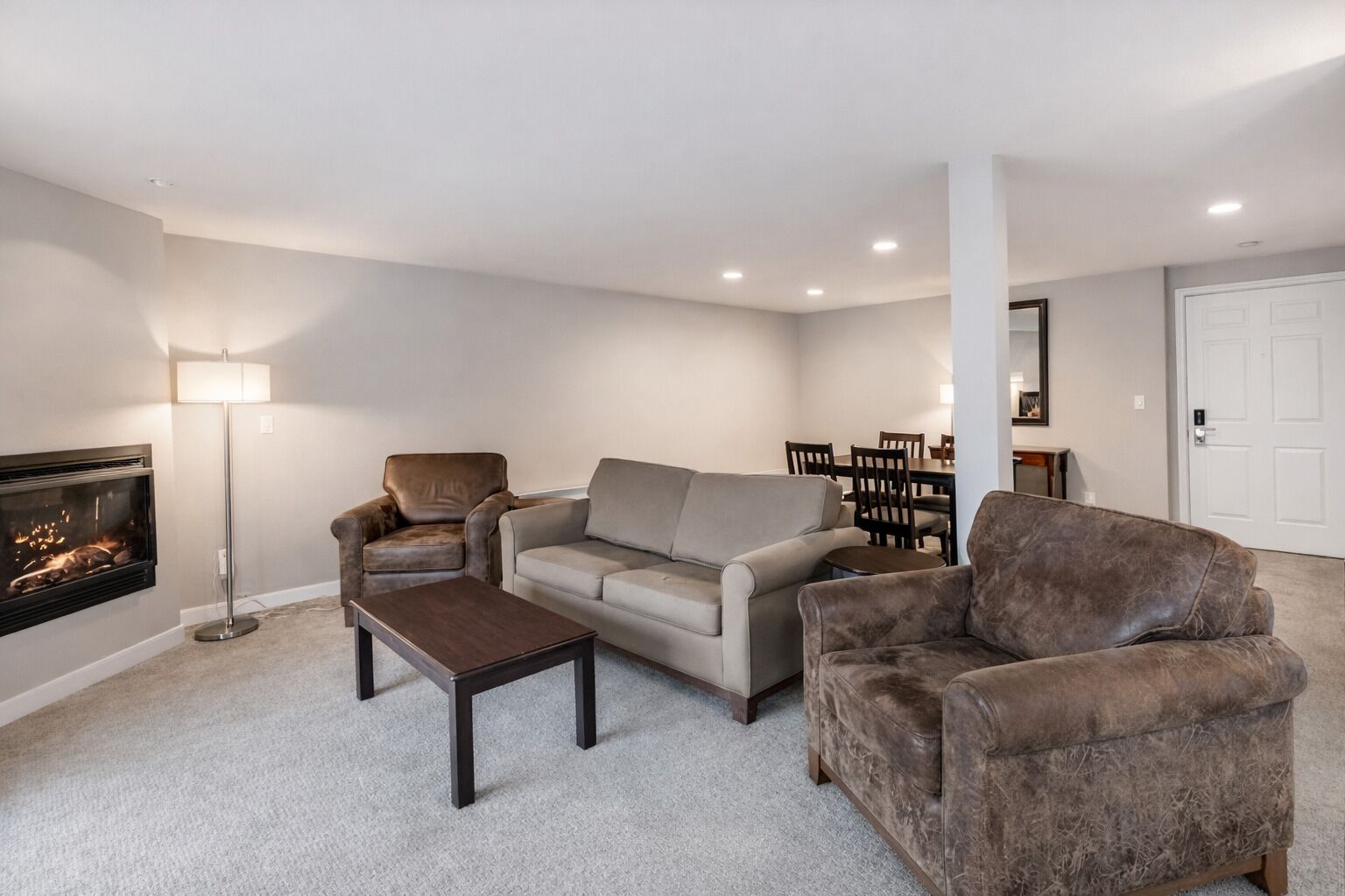 A living room with a fireplace, a sofa, a coffee table, and a chair.