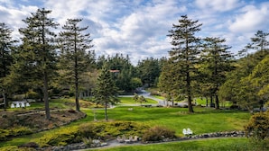 A golf course with a well-maintained lawn, trees, and a winding road. - Rosario Resort (Eastsound)