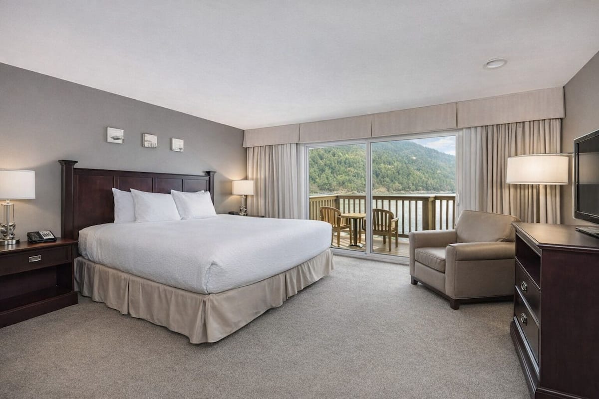 Hotelkamer met een groot bed, een bureau, een stoel, een televisie en een balkon met uitzicht op de bergen.