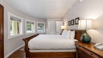 A bedroom with a large bed, a wooden dresser, a lamp, and a telephone.