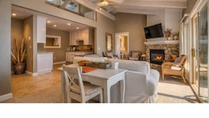 A spacious living area with a fireplace, a dining table with chairs, and a kitchen in the background. - Rosario Resort (Eastsound)