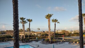 A poolside area with lounge chairs and umbrellas, surrounded by palm trees. - WorldMark Oceanside - 1 Bedroom Accessible (Oceanside)