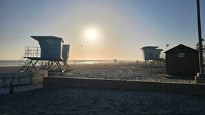 A beach with lifeguard towers and a small building, likely a lifeguard station. - WorldMark Oceanside - 1 Bedroom Accessible (Oceanside)