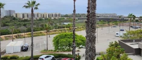 A parking lot with several cars, palm trees, and a building in the background.