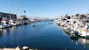 Una marina con barcos amarrados a lo largo del agua, un cielo despejado y una costa rocosa.