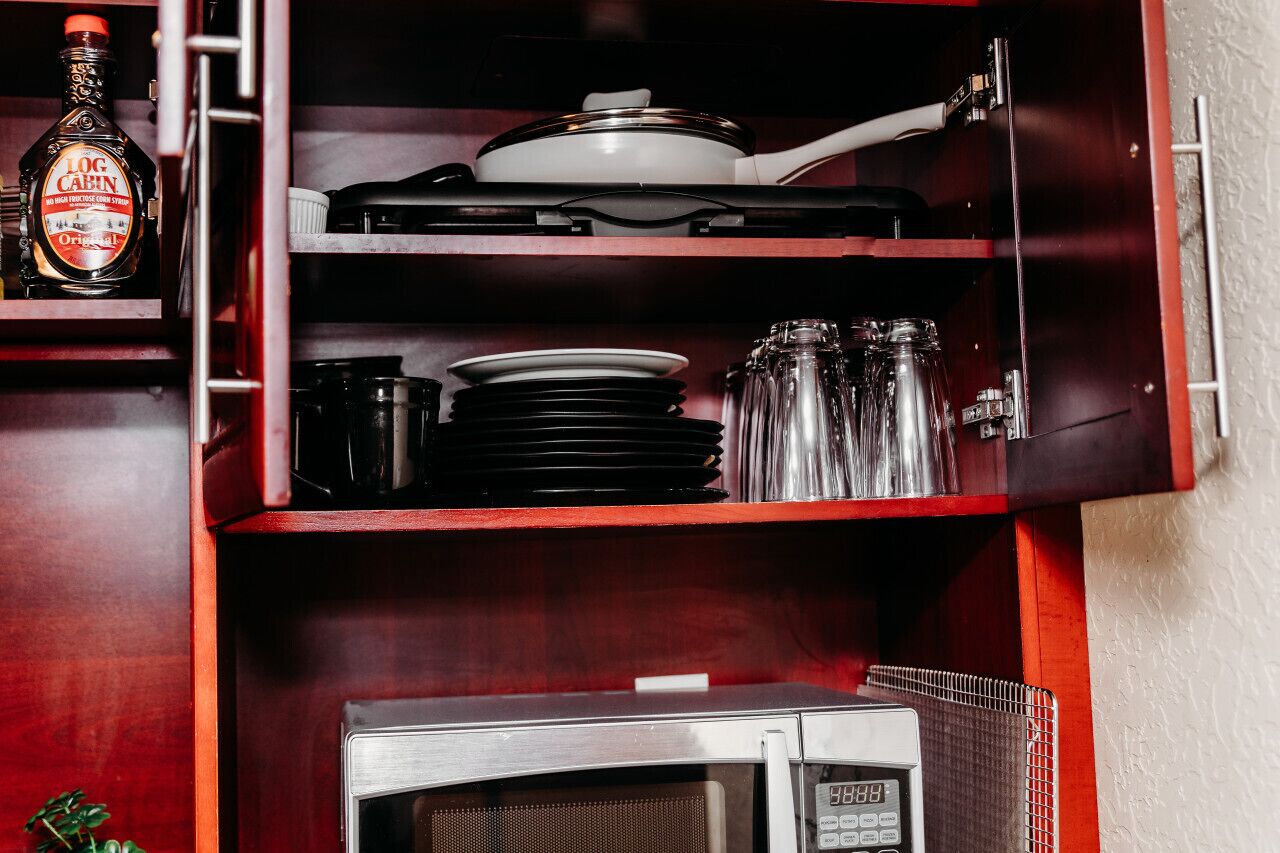A kitchen with a microwave, a stove, and a bottle of liquor.