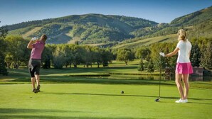 A golf course with two players, a pond, and rolling hills in the background. - Ski in and out, Canyons, Westgate, King, Kitchen, Free Breakfast, Coffee & Tea Bar, Steam, Pool, HT (Park City)
