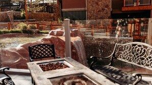 An outdoor seating area with stone walls, a small waterfall, and a fire pit. - Ski in and out, Canyons, Westgate, King, Kitchen, Free Breakfast, Coffee & Tea Bar, Steam, Pool, HT (Park City)