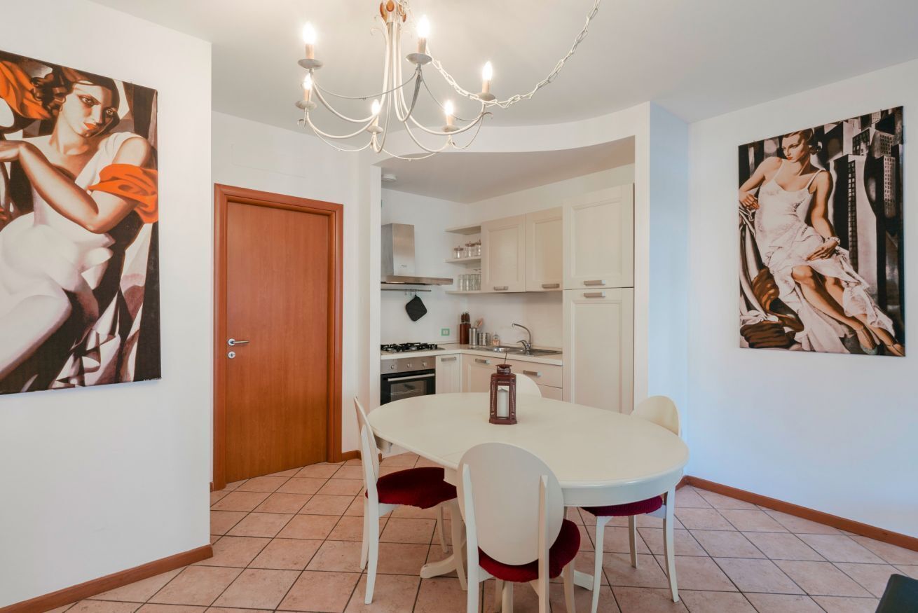 A dining area with a round table, white chairs, and a chandelier.