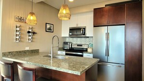 A modern kitchen with a central island, stainless steel appliances, and pendant lighting. - Lovely Condo with Stunning Ocean View (Playas de Rosarito)