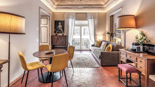 A spacious room with a dining area, a sofa, a desk, and a view through a glass door to the outside. - Corso 142 elegant apartment within walking distance of Piazza Navona (Roma)