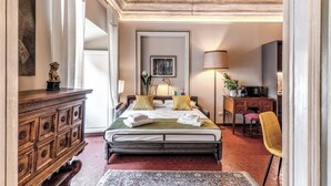 A well-lit bedroom with a large bed, a wooden dresser, a desk with a chair, and a lamp. - Corso 142 elegant apartment within walking distance of Piazza Navona (Roma)