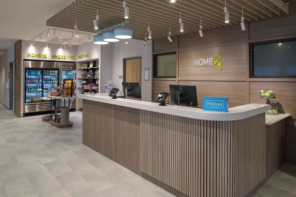 A hotel reception area with a modern design, including a reception desk, a minibar, and a seating area.