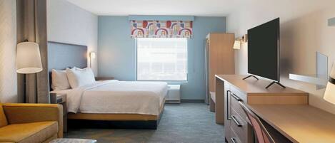 A hotel room with a bed, a desk, a chair, a TV, and a window with curtains.