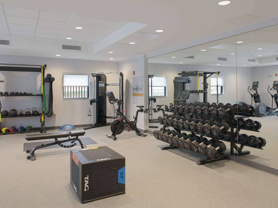 Una palestra con attrezzatura per sollevamento pesi, tapis roulant e uno specchio a parete.