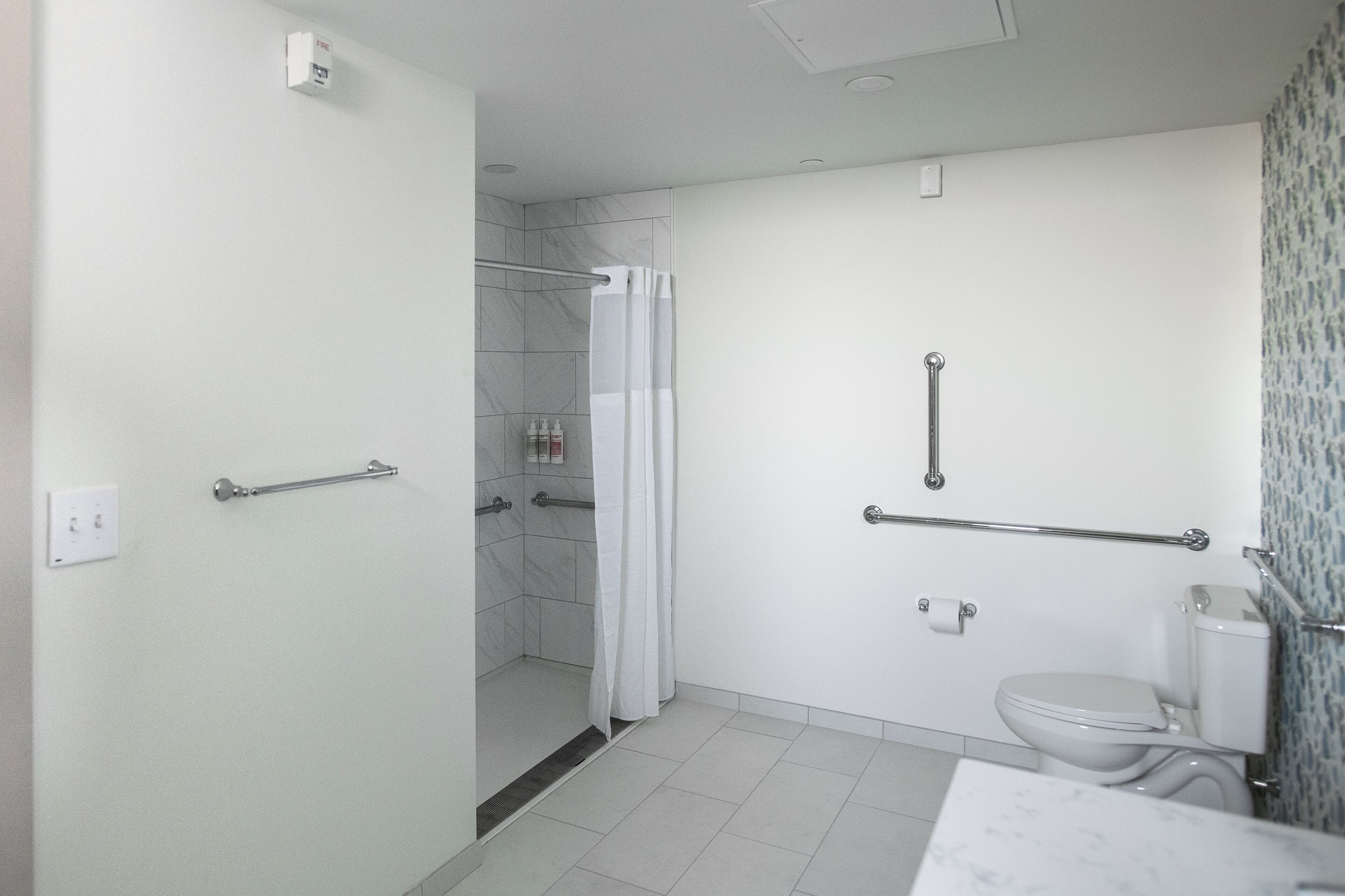 A modern bathroom with a shower, toilet, and a handrail for accessibility.