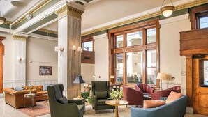 Un vestíbulo amplio con suelo de mármol, sofás de cuero, un sillón verde y un sillón azul.