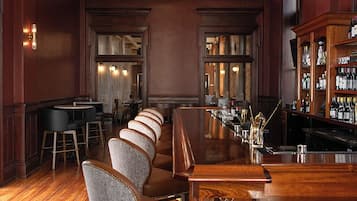 Un espace bar doté d’un long comptoir, de tabourets de bar et d’un lustre.