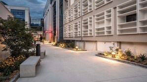 A modern hotel with a spacious outdoor area, a visible sign for 'Hampton', and a well-lit pathway. - Hampton By Hilton Locarno (Losone)