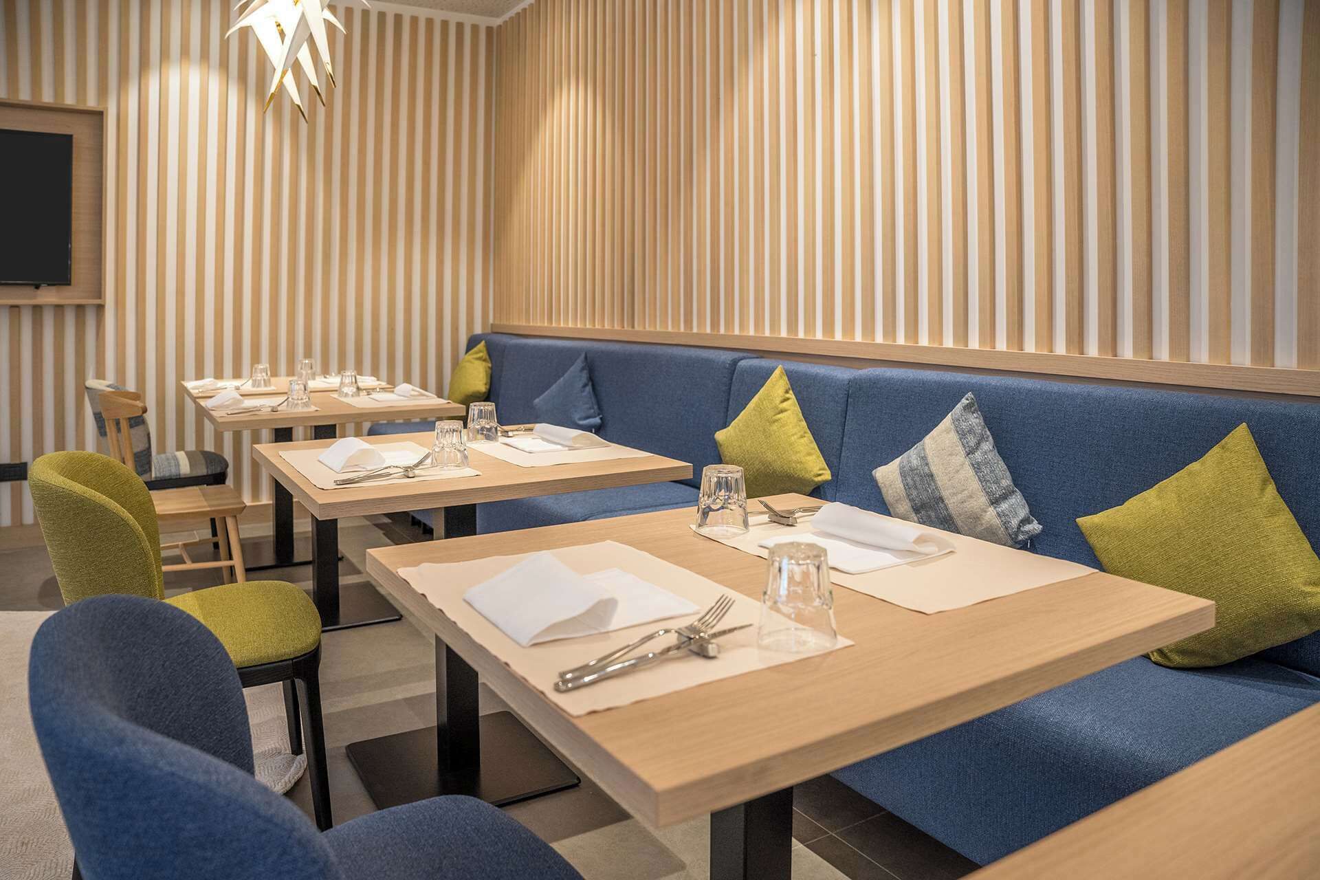 Ein Restaurant mit Holztischen und blau gepolsterten Sitzplätzen.