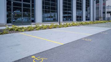 Un espace de stationnement avec des places délimitées, dont une place réservée aux personnes handicapées, situé devant un bâtiment moderne doté de grandes fenêtres.