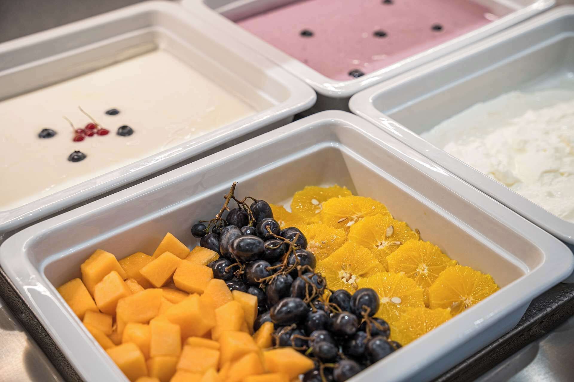 Eine Auswahl an Obst und Joghurt in einem Buffet-Bereich.