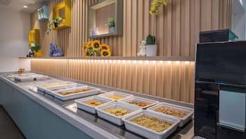 A buffet area with various food options, a television, and decorative plants.