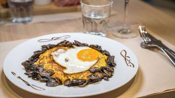 A plate of food with a fried egg and mushrooms, accompanied by a glass of water and a wine glass.