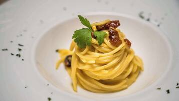 En tallrik pasta, garnerad med persilja och en liten bit kött.