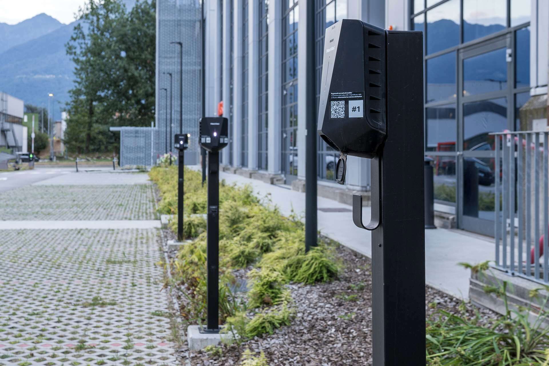 A modern building with a glass facade and a parking meter in the foreground.
