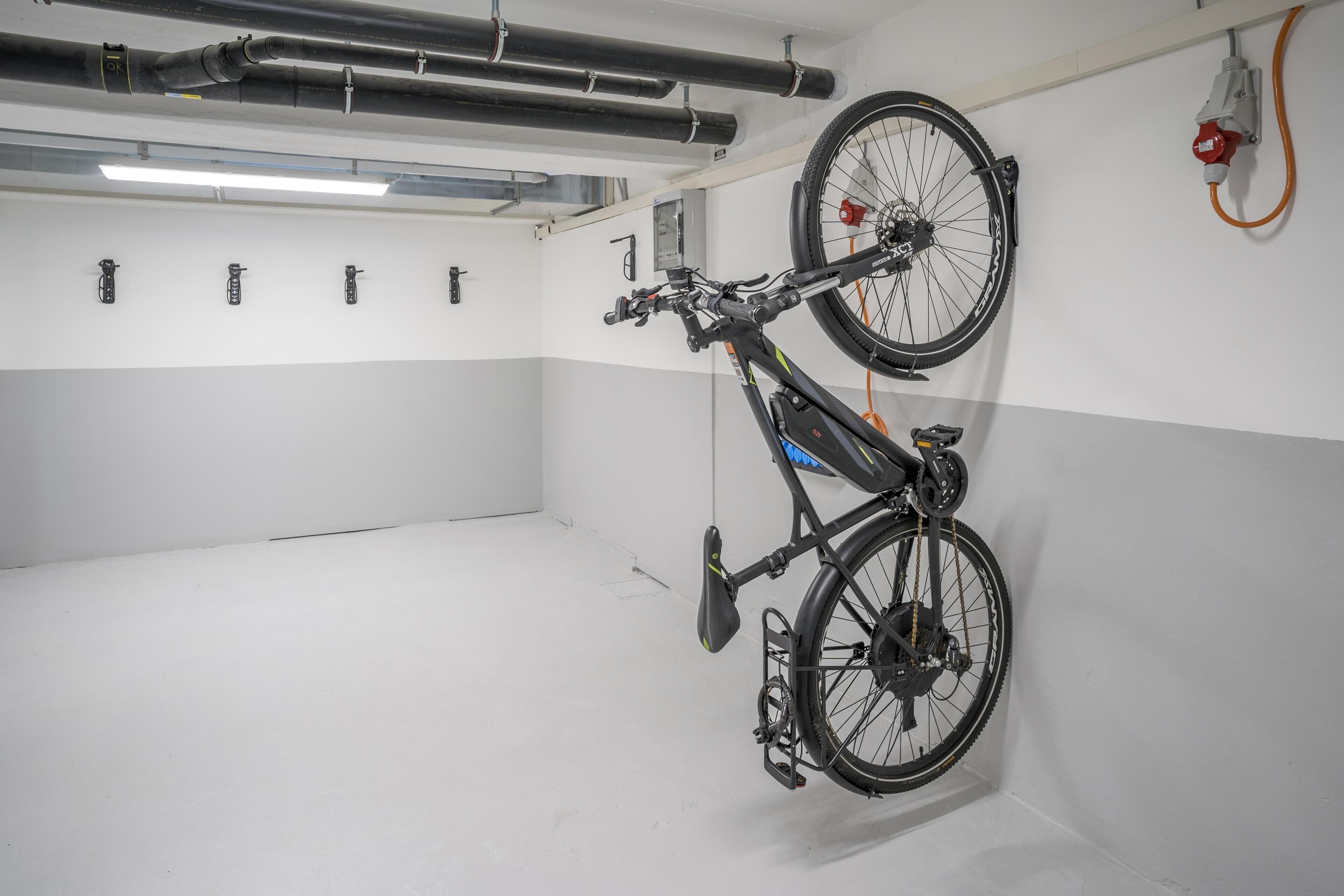A bicycle mounted on a wall in a room with white walls and a clean floor.