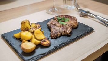 Un plato de carne a la parrilla y patatas asadas sobre una tabla de pizarra.