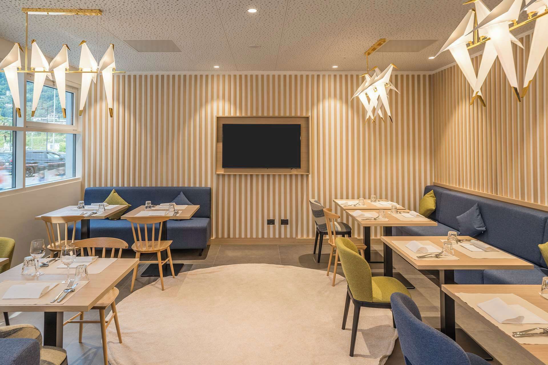 Un área de comedor moderna con paredes a rayas, un televisor de pantalla plana y una variedad de opciones de asientos, incluyendo mesas y sofás.