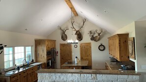 A spacious kitchen with wooden cabinets, a stone island, and deer antlers mounted on the wall. - Turtle Bay Lodge 
Great for Large Gatherings (Port O'Connor)