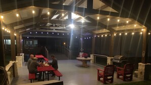 An outdoor patio area with tables and chairs, a barbecue grill, and string lights. - Turtle Bay Lodge 
Great for Large Gatherings (Port O'Connor)