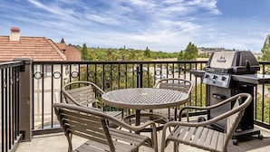 An outdoor patio with a round table and two chairs, a grill, and a view of a residential area. - WorldMark Solvang - 1 Bedroom Accessible (Solvang)