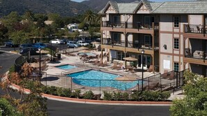 A hotel with a pool area, multiple balconies, and a view of mountains. - Solvang | Wine Country Hideaway | Pool & Village Walks (Solvang)