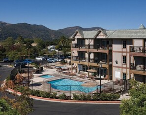 A hotel with a pool area, multiple balconies, and a view of mountains. - Solvang | Wine Country Hideaway | Pool & Village Walks (Solvang)
