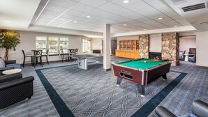 A pool table in a well-lit room with a patterned carpet, a seating area with chairs, and a stone fireplace. - Solvang | Wine Country Hideaway | Pool & Village Walks (Solvang)