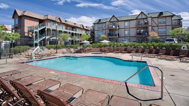 A swimming pool with lounge chairs and a building with balconies in the background. - Solvang | Wine Country Hideaway | Pool & Village Walks (Solvang)