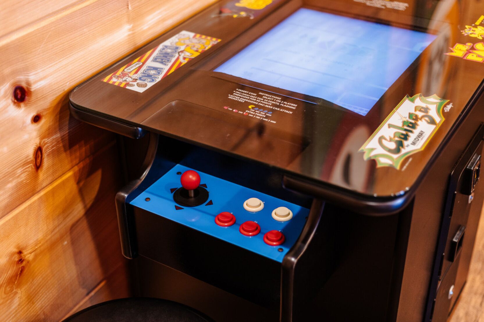 A vintage arcade machine with a joystick and buttons, featuring a screen and various labels.