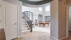 A spacious interior with a curved staircase, a pool table, and a chandelier. - Elegant desert getaway. 4 bedroom 2.5 bath. Sleeps 8. Heated pool. Outdoor BBQ. (Oro Valley)