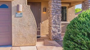 A house with a stone facade, a garage door, and a well-maintained front yard. - Elegant desert getaway. 4 bedroom 2.5 bath. Sleeps 8. Heated pool. Outdoor BBQ. (Oro Valley)